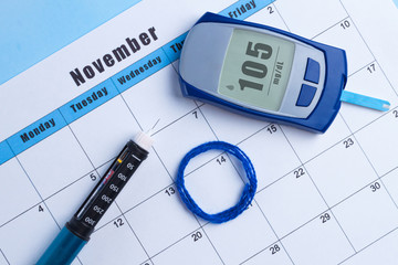 Diabetes.  World Diabetes day, 14 November. Diabetes concept. Glucose meter and pen syringe lying...