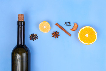 Ingredients for mulled wine. Bottle of red wine, lemon, anisetree, spices, cinnamon, orange on a blue background. Winter drinks