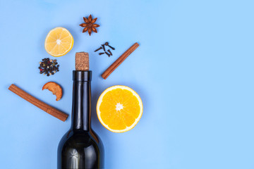 Ingredients for mulled wine. Bottle of red wine, lemon, anisetree, spices, cinnamon, orange on a blue background. Winter drinks