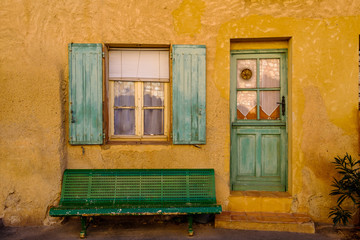 Façade d'une maison en Provence. Mur de couleur jaune (ocre), porte et fenêtre vertes.