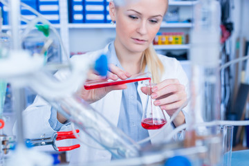 Female laboratory assistant with chemical experiment in scientific laboratory. Female medical or scientific researcher using test tube on laboratory.