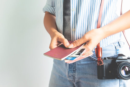 Female tourist holding passport and Thai currency, Travel concept