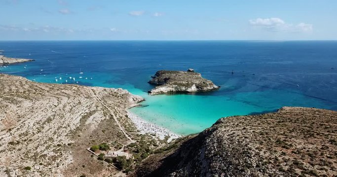 Aerial view of Isola dei Conigli next to the island of Lampedusa, Sicily, Italy with Mediterranean sea. Italian summer landscape seen from the sky with drone flying over beach