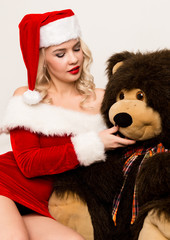 sexy christmas girl embraces with a big teddy bear. blonde woman dressed as Santa