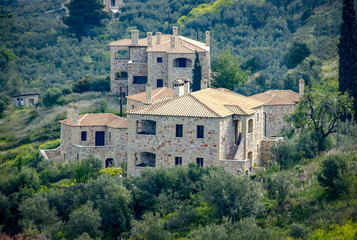 Fototapeta na wymiar New built luxurious stone house with ceramic roofs surrounded by green nature. Greece
