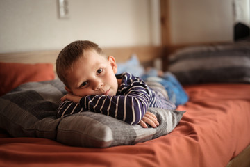 serious boy hugs pillow on couch, loneliness.