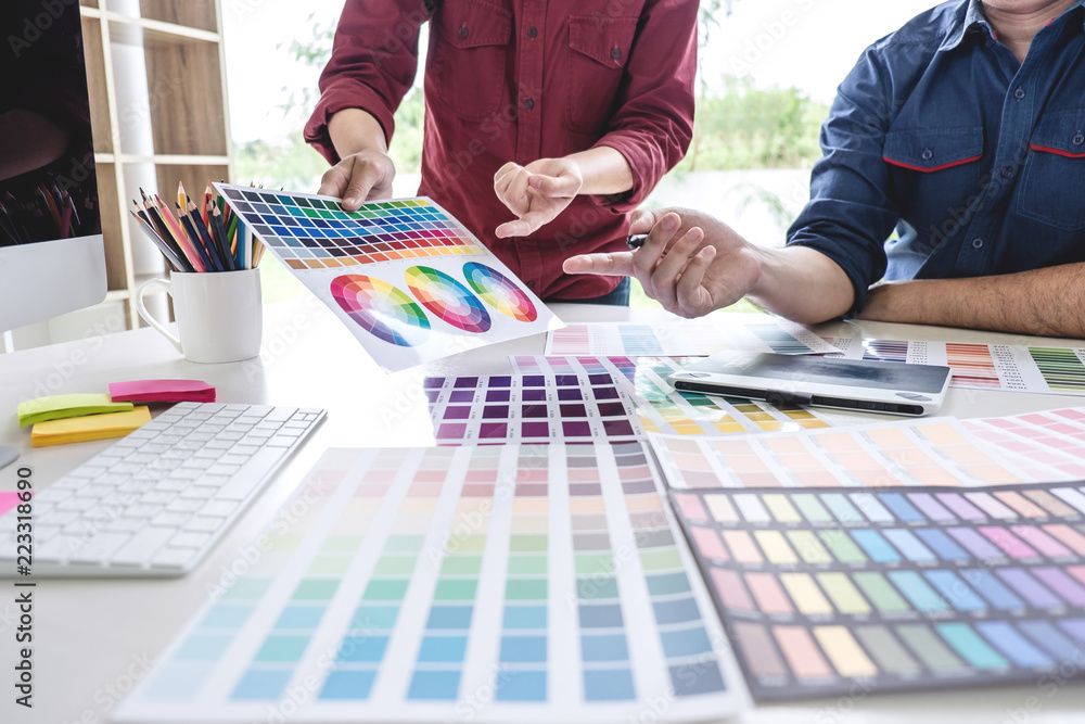Poster Two colleagues creative graphic designer working on color selection and drawing on graphics tablet at workplace