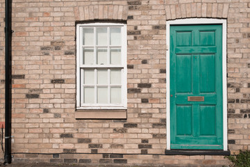 Green pastel vintage front door on a restored brick wall of a Georgian house residential building with white wooden sash window