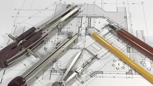 Blueprints - architectural drawings and compasses and pencils smoothly rotate on the surface of the architectural plan of a modern house
