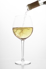 pouring white wine into glass, on white background