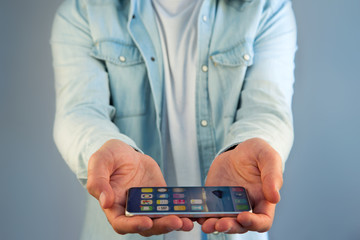 Young man giving an empty hand with smartphone on a color background