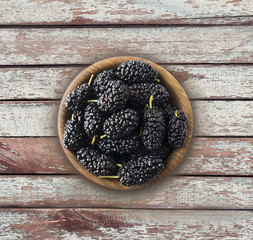 Mulberries in a wooden bowl with copy space for text. Ripe and tasty mulberry on a wooden...