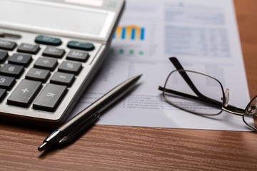 office documents with a pen, calculator, and eye glasses
