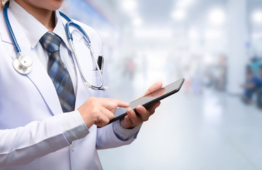 smart woman doctor holding tablet and pointing to screen on blurry out patient department of...