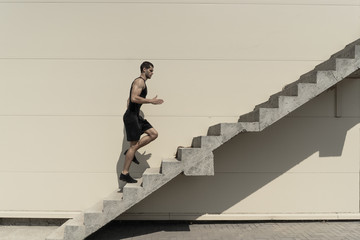 Full length shot of healthy athletic man climbing up on stairs.
