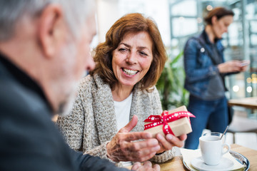 Senior couple with a present in a cafe. Christmas time.