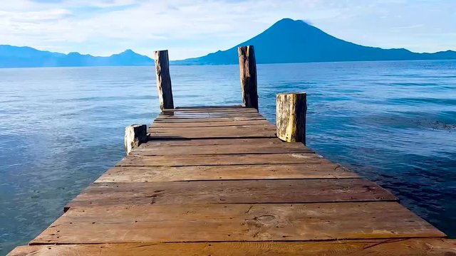 Walking on the bridge seeing the landscape of Amatitlan lake and a beautiful volcano in a sunny day with blue sky and montains.