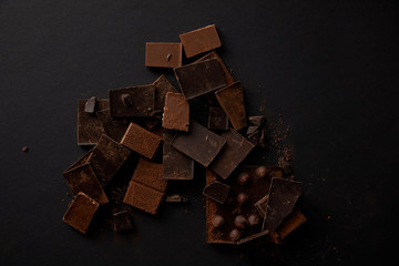 top view of gourmet chocolate pieces with hazelnuts on black