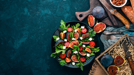 Fresh salad with figs, arugula leaves, cherry tomatoes and feta cheese. Free space for text. Top view.