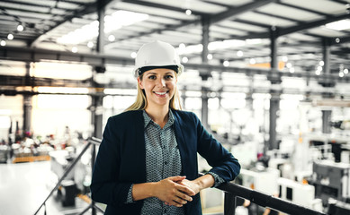 A portrait of an industrial woman engineer standing in a factory.