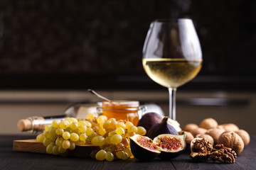 Juicy fresh whole fig fruits and one cut figs and bowl of honey in honeycombs on wooden cutting board