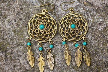Indian spiritual ornamental style brass earrings on rocky background