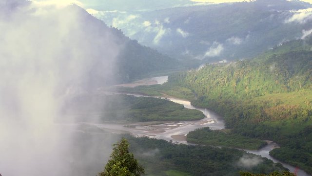 The Rio Abanico Valley, Ecuador, with misty cloudforest covered hillsides. Farmsteads cleared from forest illuminated by evening sun.  On the Amazonian slopes of the Andes in Morona Santiago province