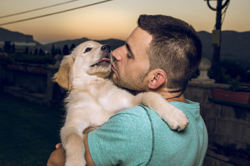 Guy with his kissing his puppy dog