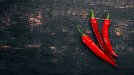 Chili red pepper. On a black wooden background. Free space for text. Top view.