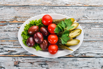 Assorted pickled vegetables on a plate. On the old wooden background. Free space for text. Top view.