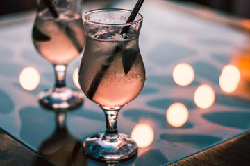 Two glasses of cocktail in the cafe with bright lights on the mirror table in the evening