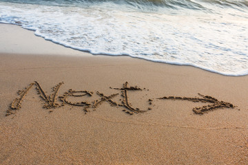 Alphabet  handwritten  in sand on beach