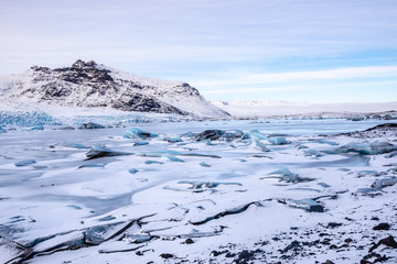 Fjallsarlon Glacial Lagoon, Iced with snow, frozen glacial ice, and moraine in a mountainous environment