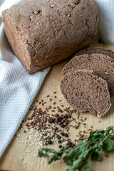 healthy rye bread on a wooden plate with spices around, white towel on the background