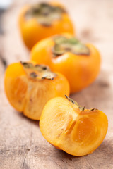 Half and sliced persimmon fruit on wooden background, healthy fruit