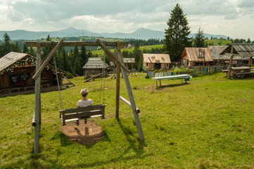 Swing in the park, girl is sitting, Carpathian mountains