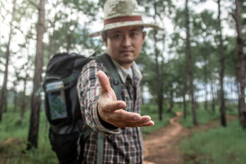 Male hiker with backpack lending a helping hand in forest