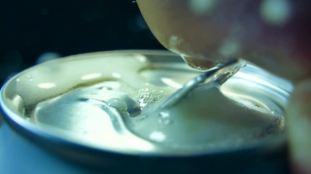 Open hand aluminum can with a drink. Drink a fresh cool drink with foam. Beer in a metal jar.