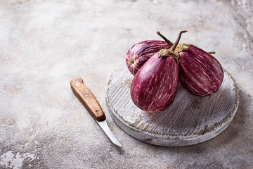 Fresh striped purple aubergines on light background