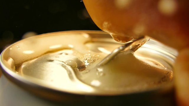 Open hand aluminum can with a drink. Drink a fresh cool drink with foam. Beer in a metal jar.