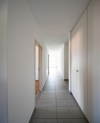 Corridor with tiles, fitted wardrobes and open doors