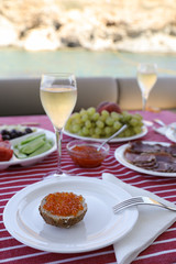 Caviar with champagne and other appetizers during summer vacation by the yacht.