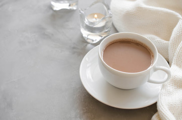 Cup of cocoa on a table, candles and knited blanket.
