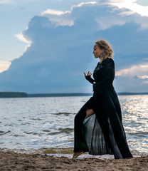 Fototapeta premium Beautiful young girl in black dress dancing on the lake