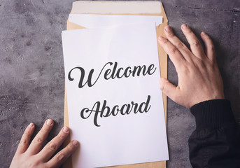 Welcome Aboard on white paper and yellow enveloppe