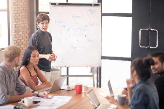 Photo of Business partners brainstoming and discussing documents about merketing plan at meeting.