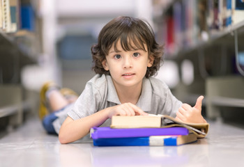 Smart boy with many books sleeping on floor .Happy Children Learning Class in Library. Development of Human Resources in Education Concept. Setup studio shooting.