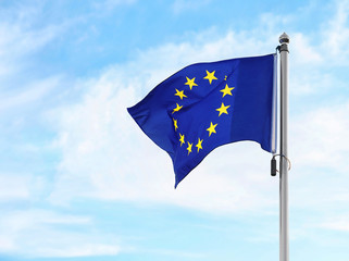 A flag of european union is flying on a background of blue sky with white clouds