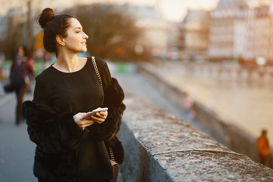 woman using her cell phone while walking through Paris