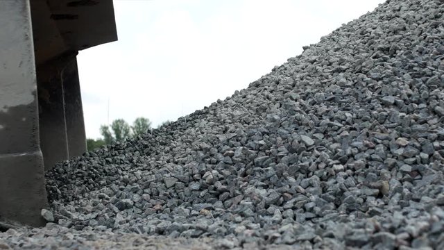 A large yellow loader collects crushed stone in a bucket, close-up, road-metal and tractor